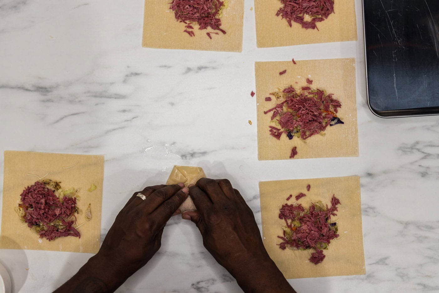 hands folding egg roll wrappers