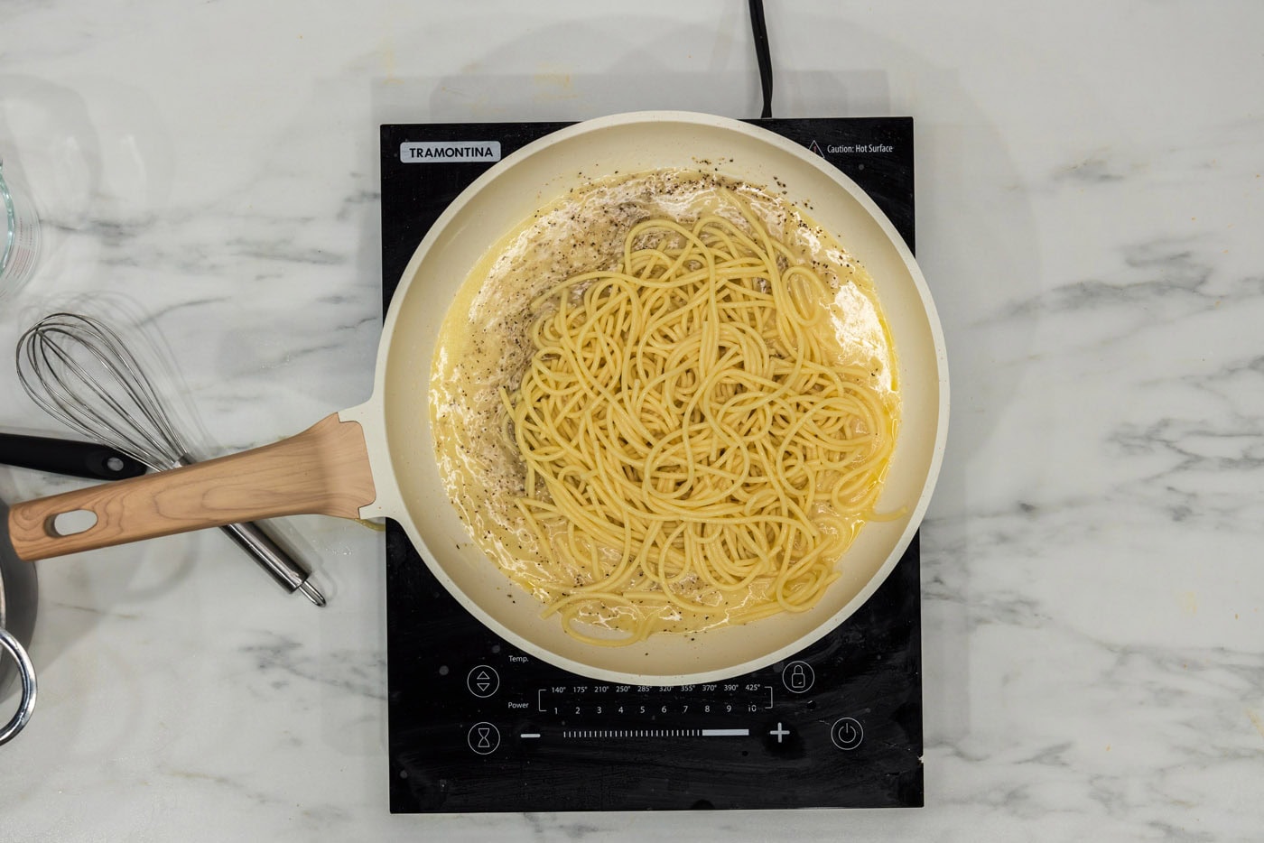 adding spaghetti to skillet with garlic and butter