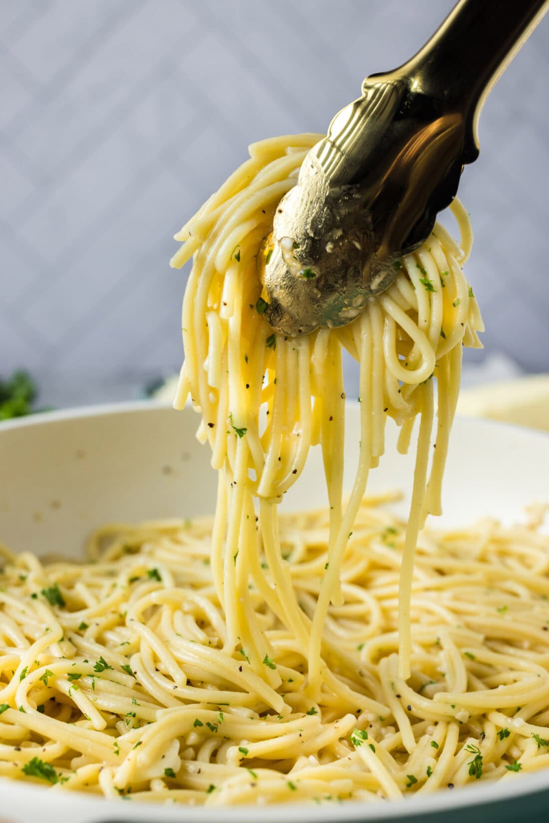 Tongs pulling up Garlic Butter Pasta from a skillet