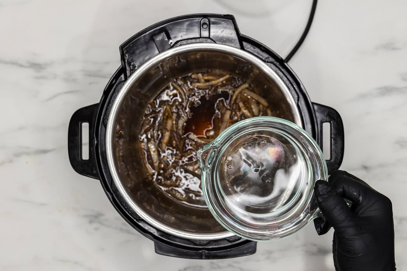 adding water to instant pot with onions, worcestershire sauce, beef base, and soy sauce