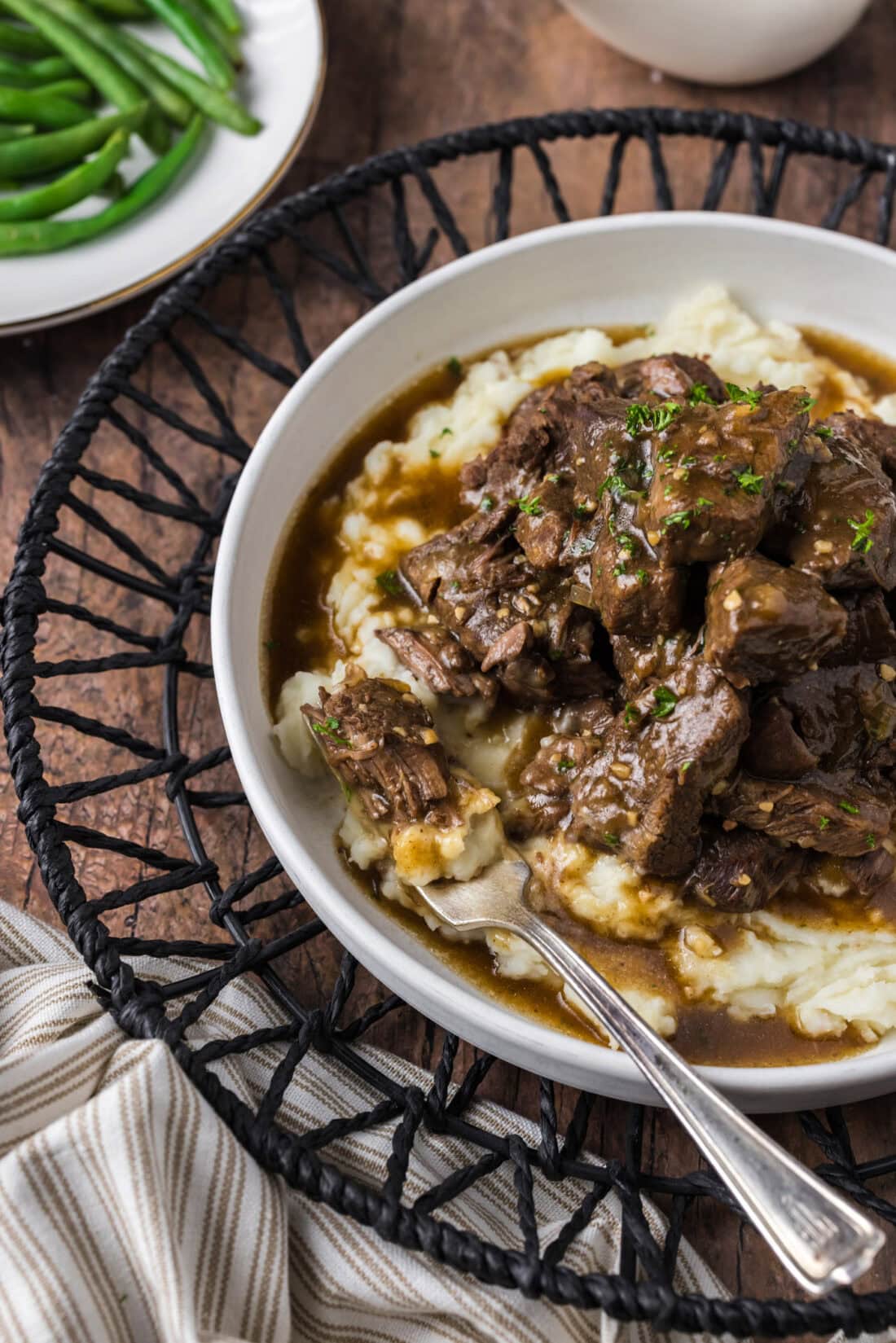 Close up photo of Instant Pot Beef Tips and Gravy served over mashed potatoes with a piece on a fork