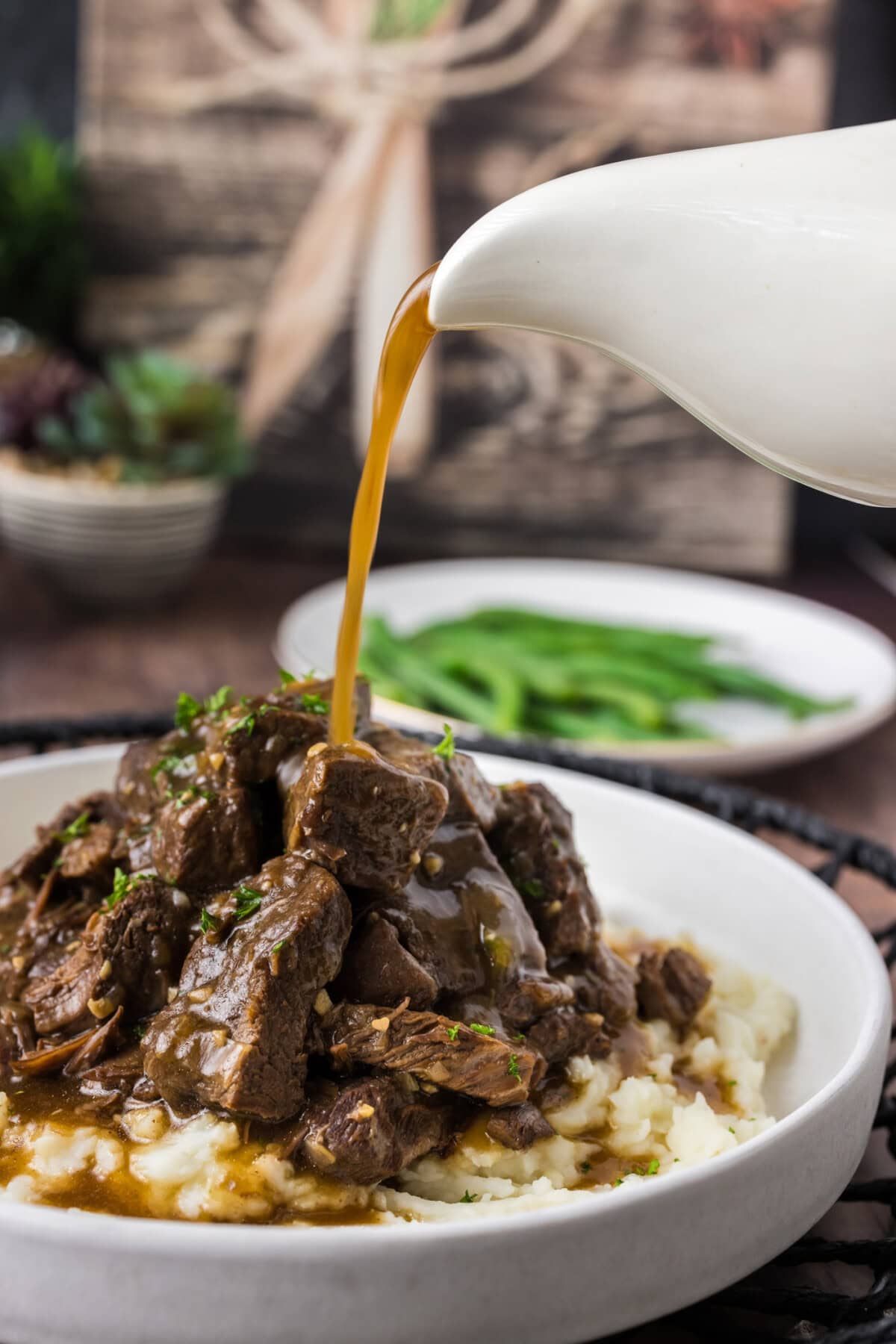 Gravy being poured over a pile of Instant Pot Beef Tips and mashed potatoes