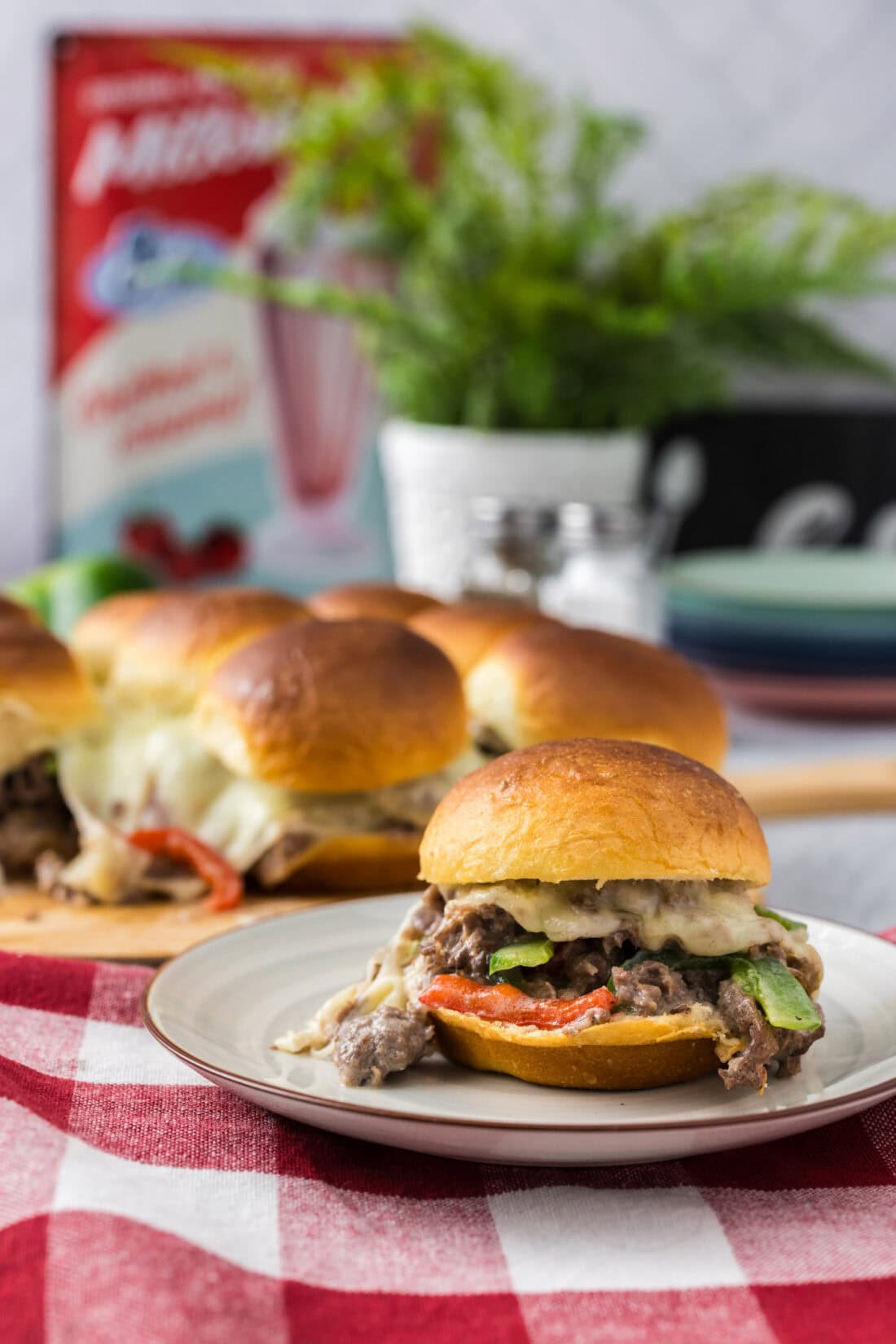 Philly Cheesesteak Slider on a plate with more Philly Cheesesteak Sliders in the background