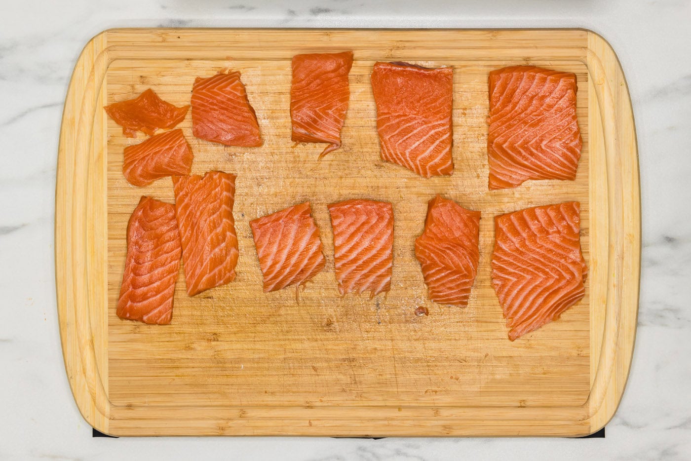 salmon cut into small portions on a cutting board