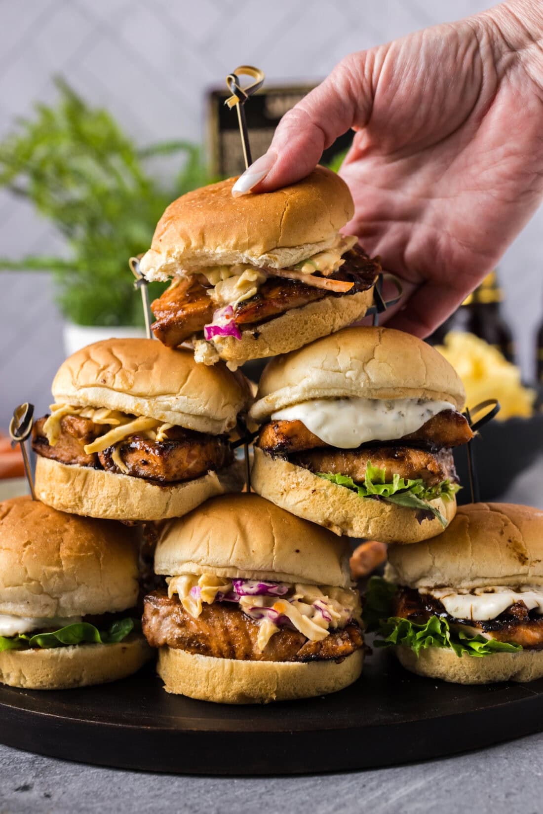 Hand placing a Salmon Slider on top a stack of Salmon Sliders