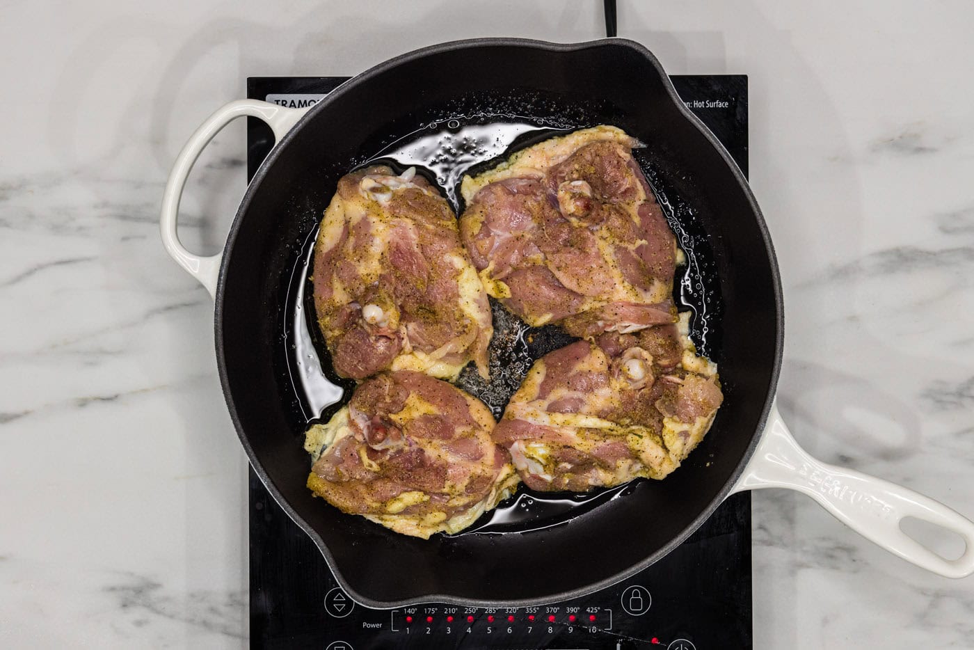 pan searing chicken thighs in a skillet with oil