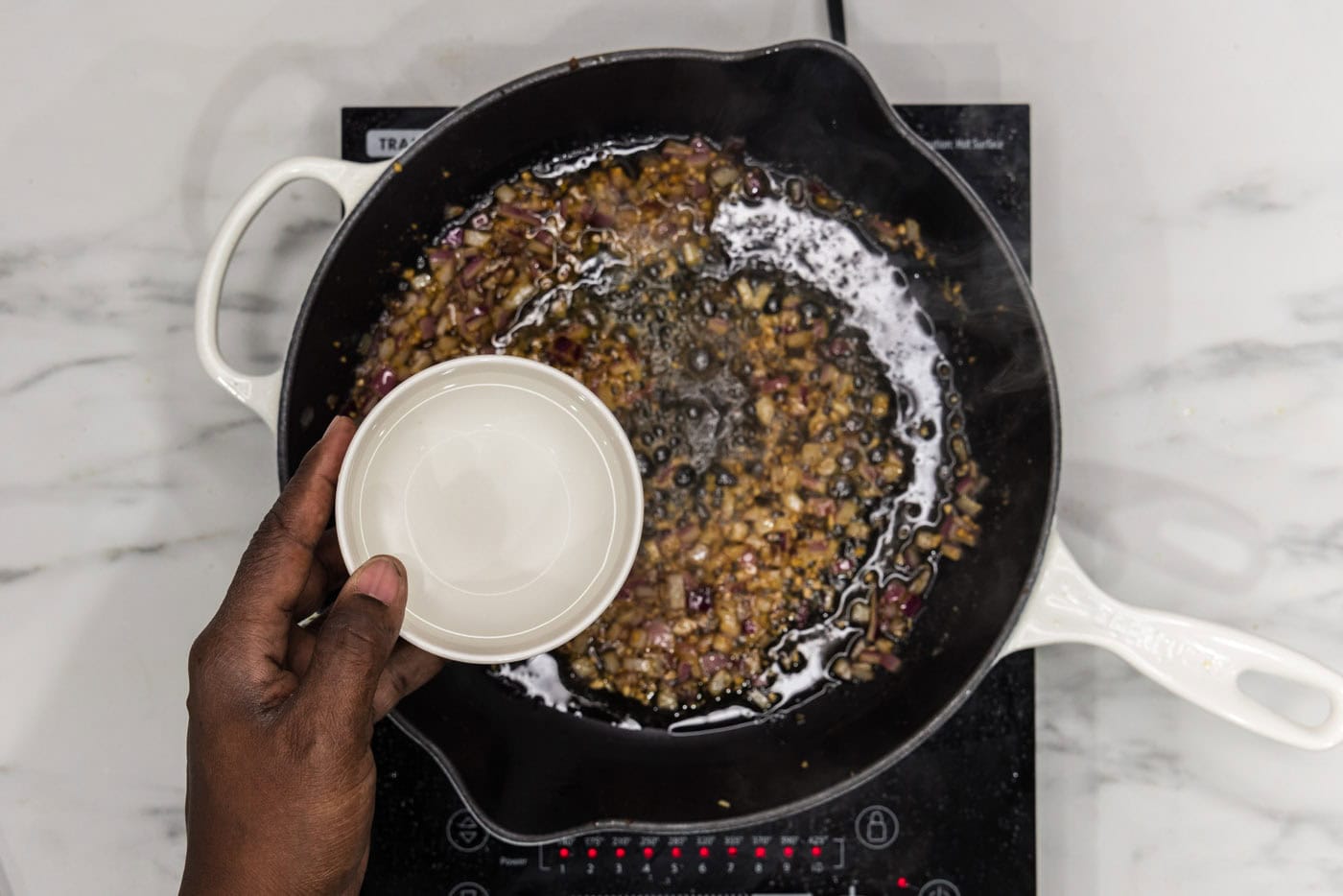 adding water to skillet with sauteed onion and garlic