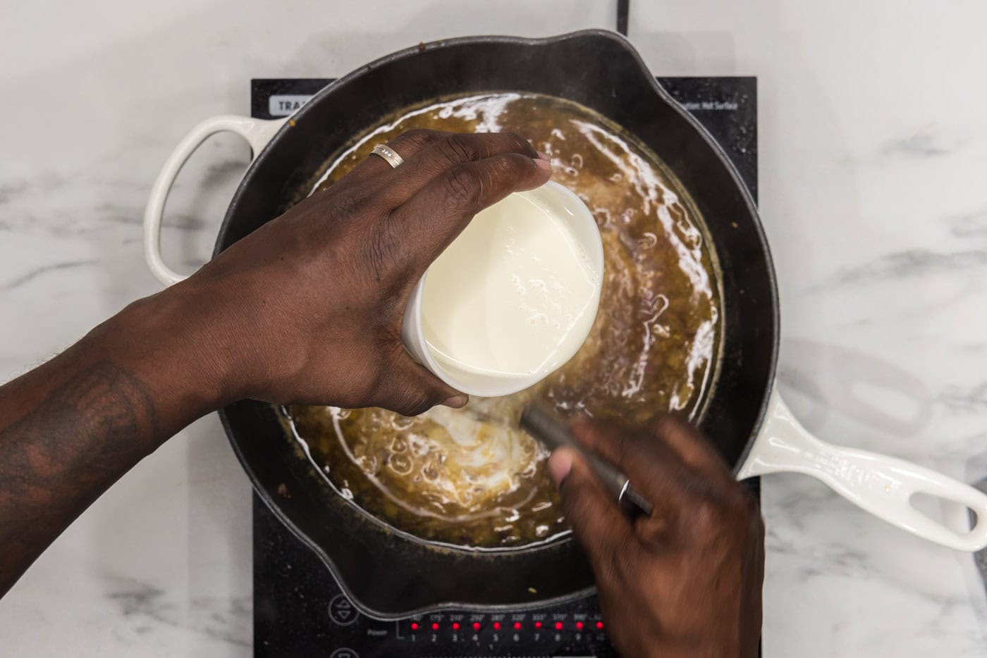 whisking heavy cream into skillet with onions and garlic