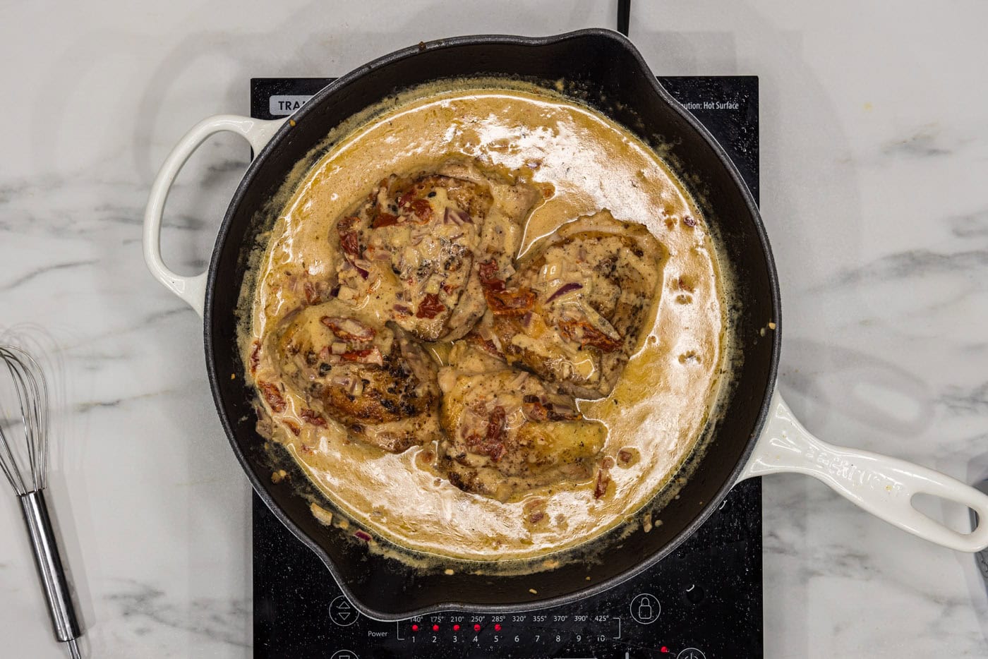 chicken thighs in a skillet with sun dried tomatoes and cream sauce