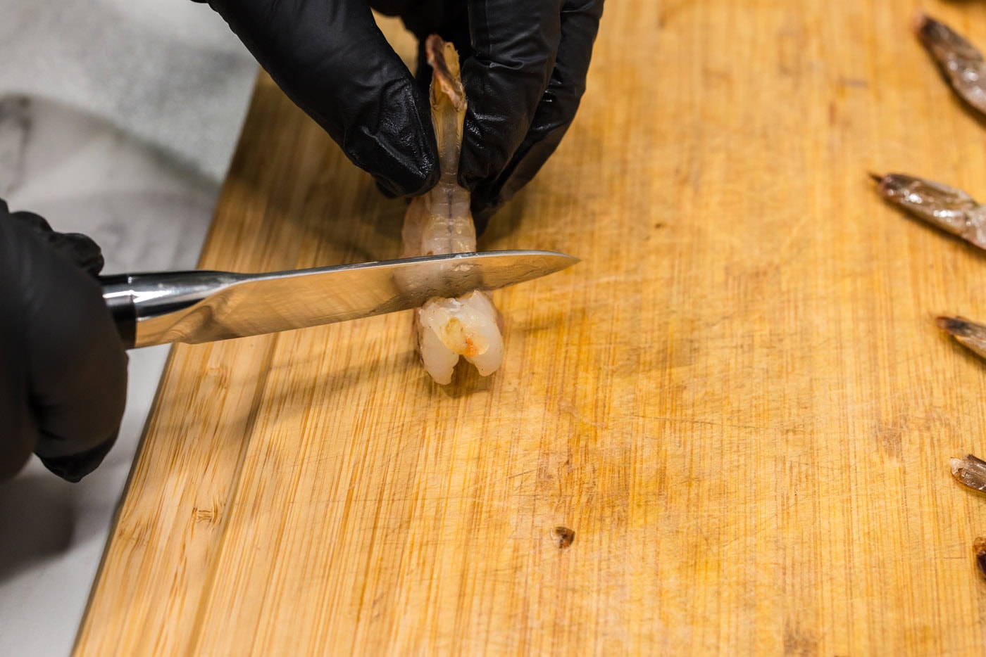 scoring shrimp with a knife on a cutting board