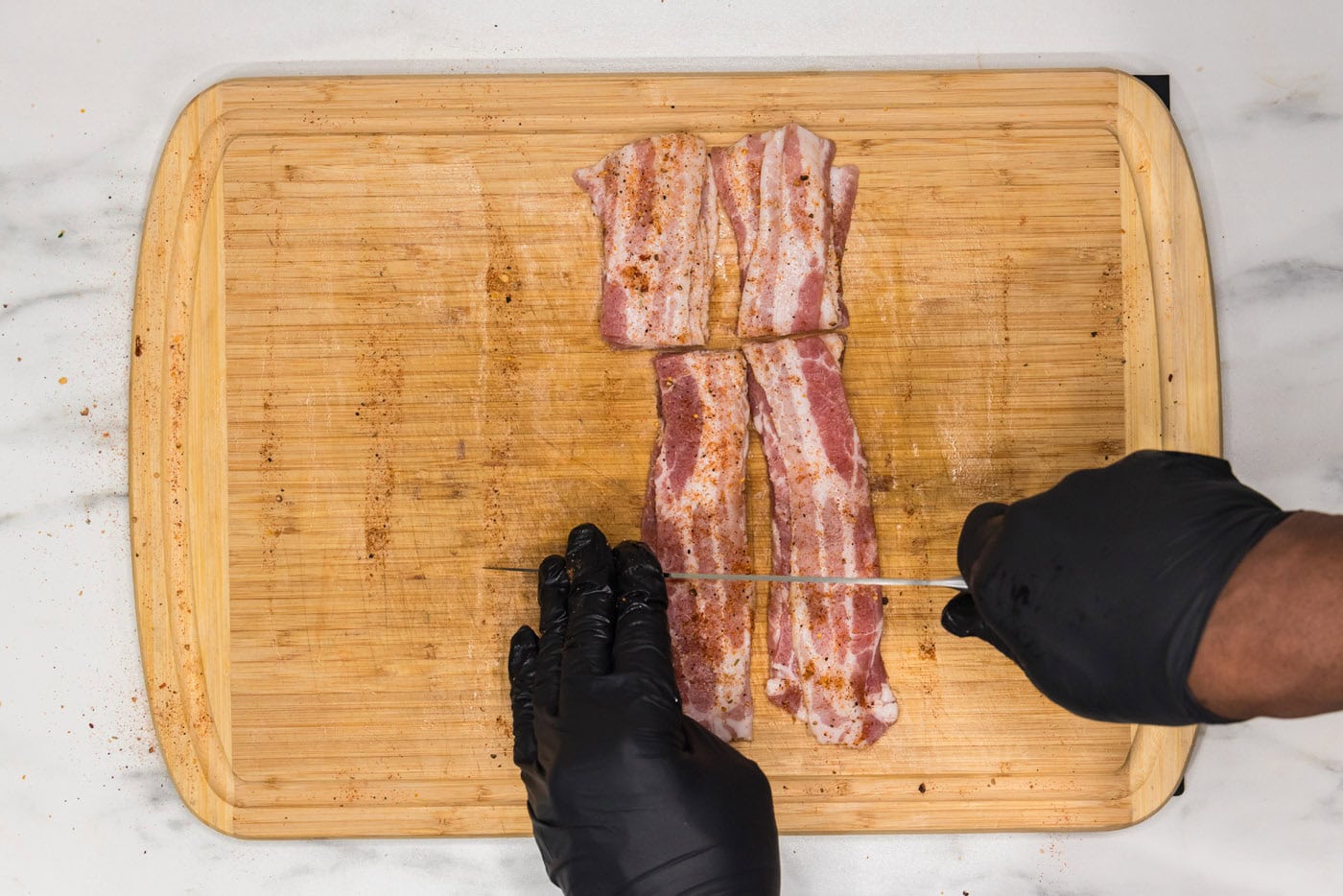 slicing bacon into thirds on a cutting board