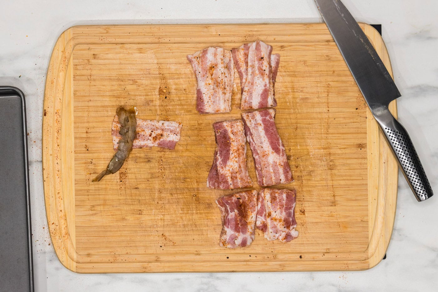 wrapping shrimp in bacon on a cutting board