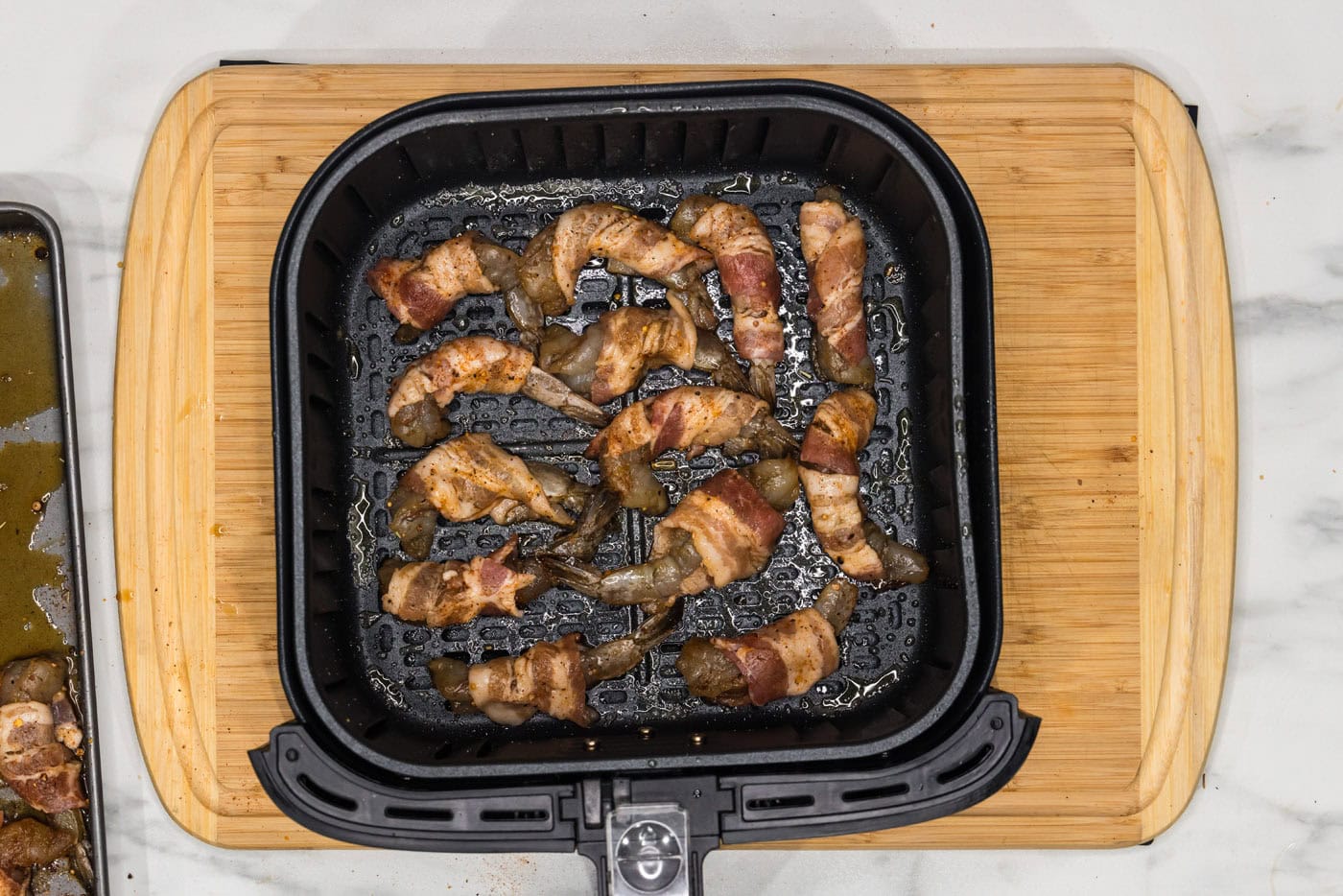 bacon wrapped shrimp in an air fryer basket