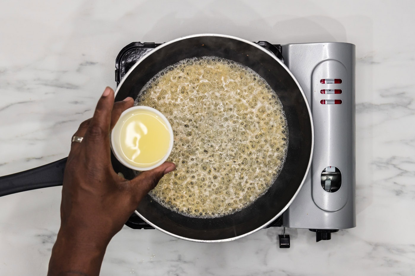 pouring lemon juice into skillet of white wine, shallots, and garlic