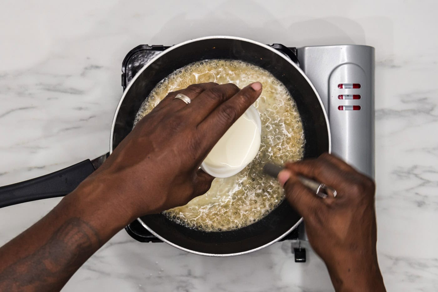 whisking heavy whipping cream into sauce in a skillet