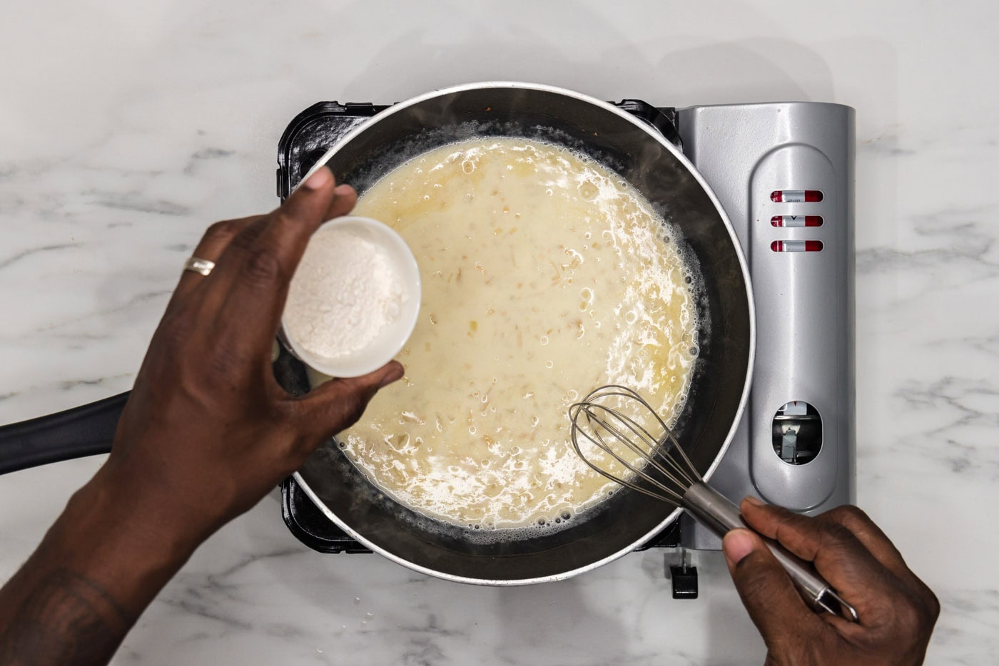 whisking flour into sauce in a skillet