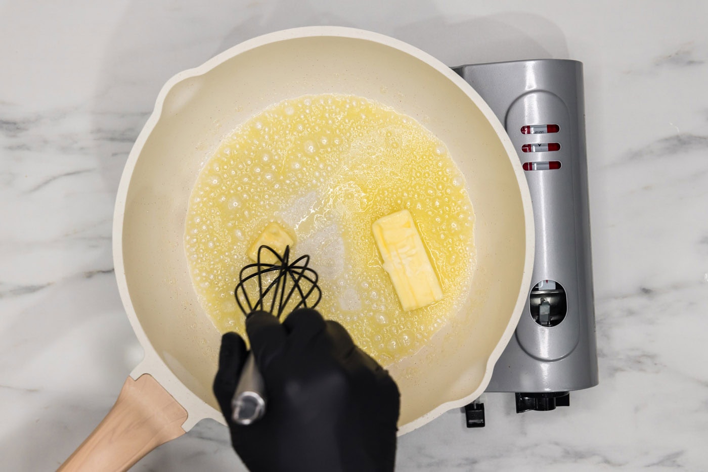 whisking butter in a skillet over heat