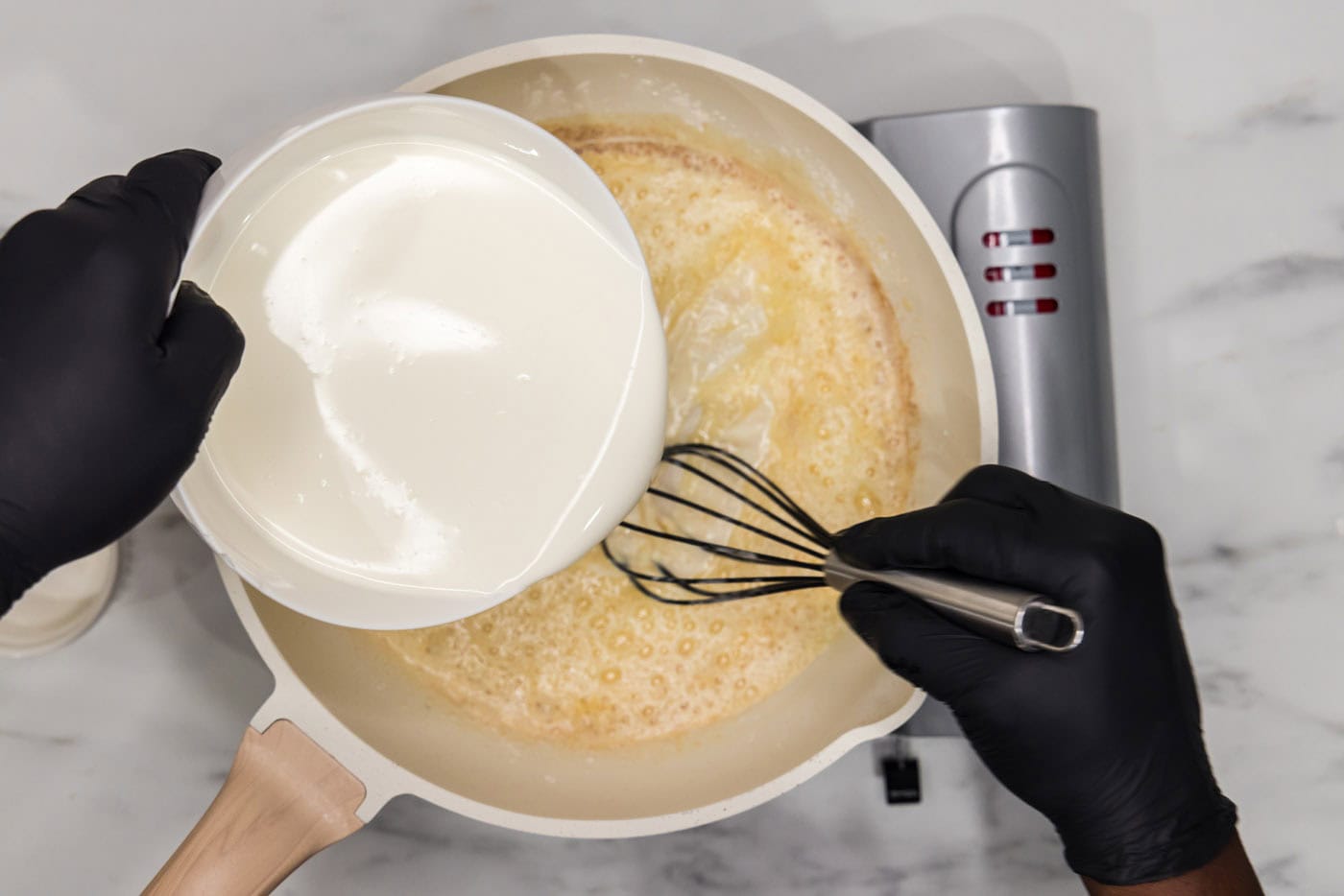 pouring half and half into a skillet with butter and flour mixture