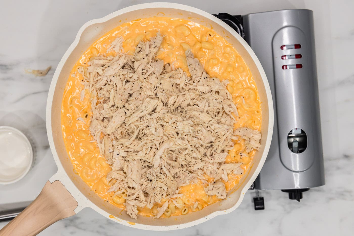 shredded chicken added to skillet of buffalo mac and cheese