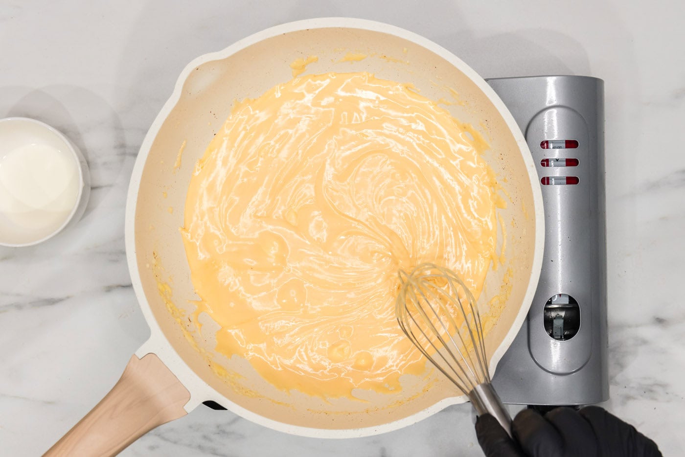 whisking cream cheese sauce in a skillet