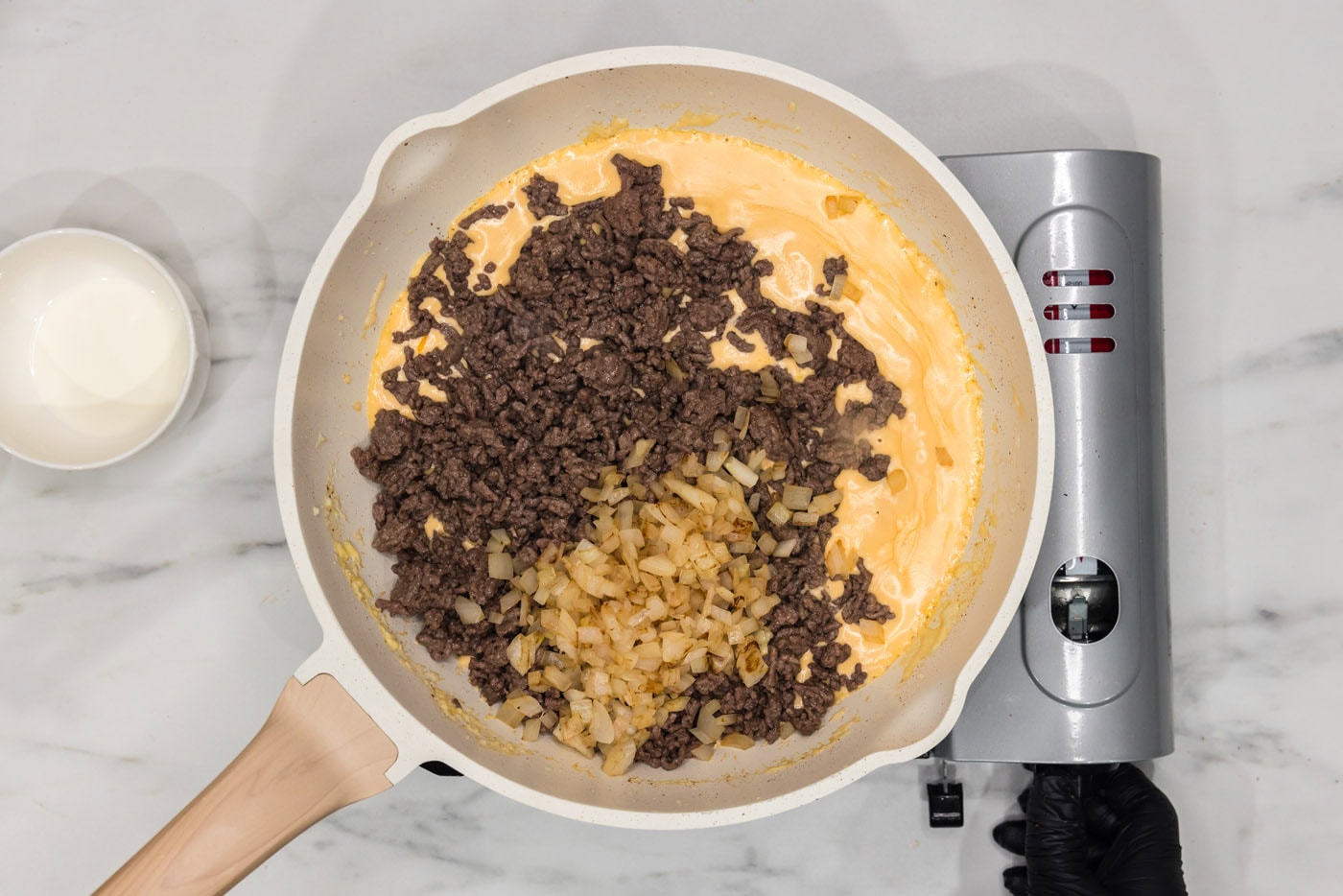 ground beef and onions added to cream cheese mixture in a skillet