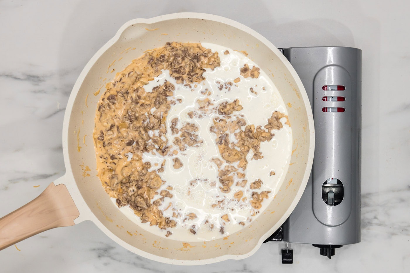 heavy cream added to cheesy beef mixture in a skillet