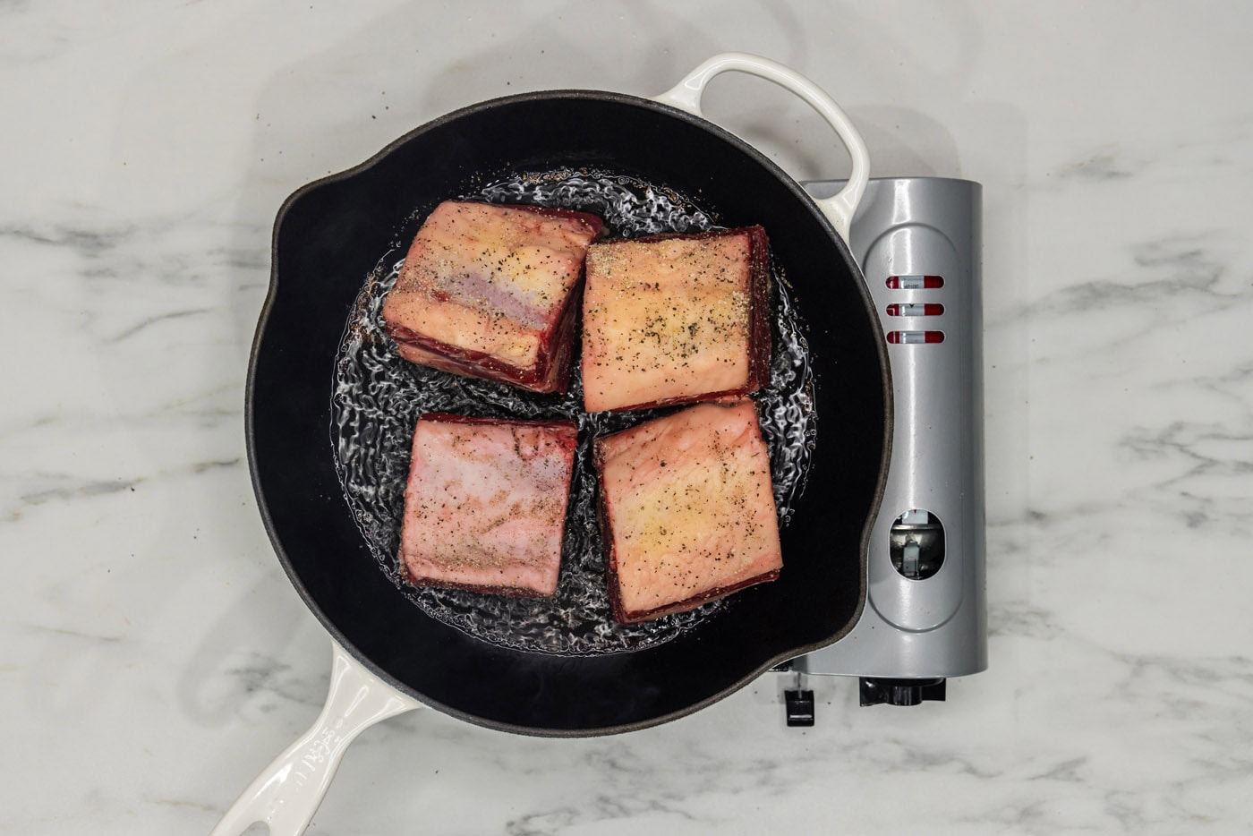 short ribs searing in a skillet