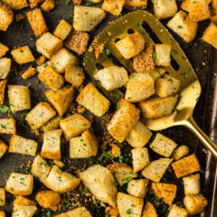 Close up photo of a spatula on a baking sheet of Homemade Croutons