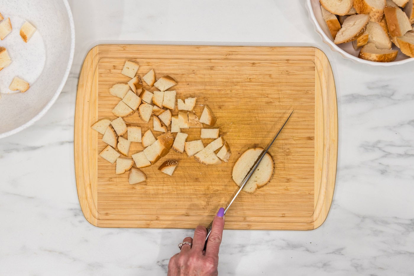 slicing breads into cubes on a cutting board