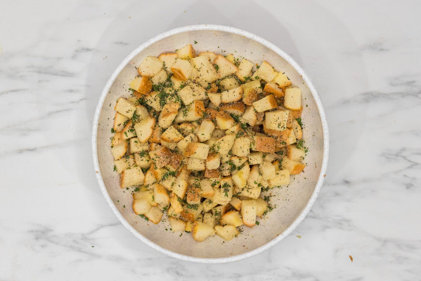 cubed bread with seasonings and herbs in a large bowl