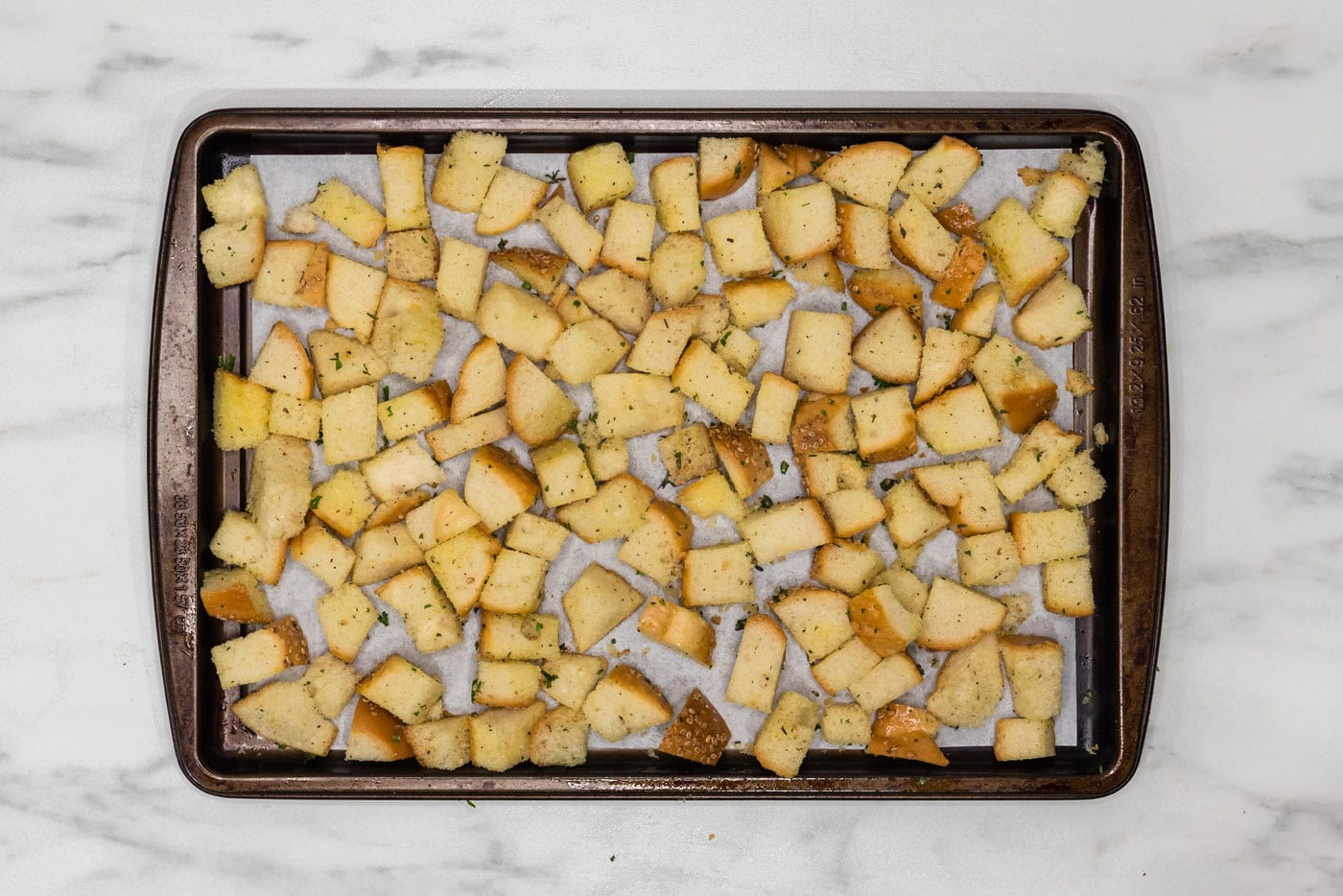 seasoned cubed bread on a baking sheet