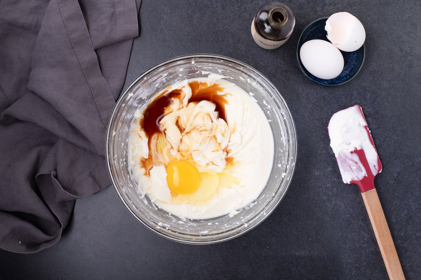 eggs and vanilla added to cheesecake batter in a bowl