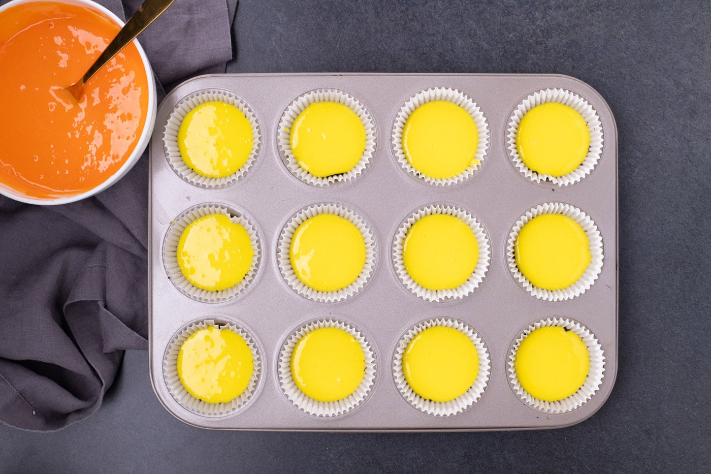 yellow cheesecake batter in a muffin pan