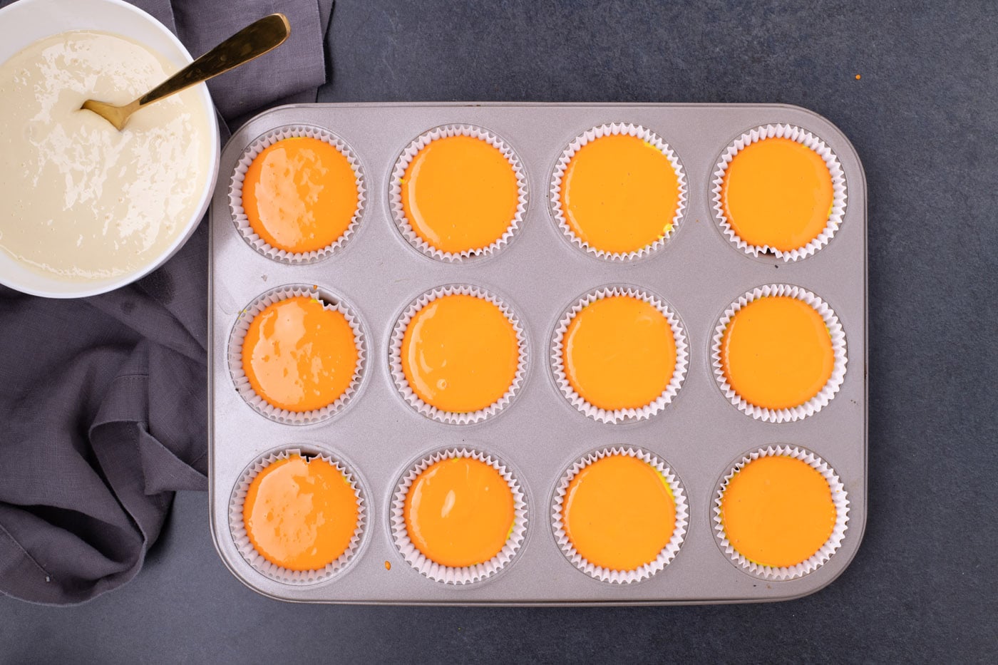 orange cheesecake batter in a cupcake pan