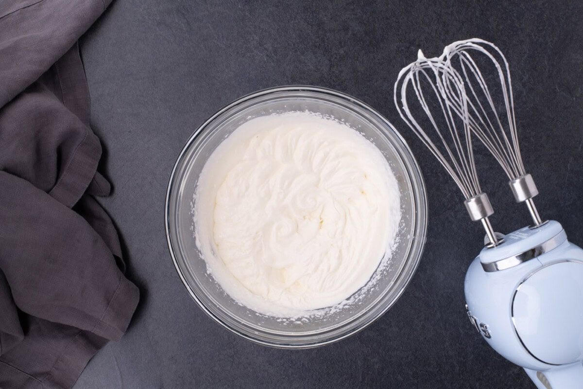whipped cream in a bowl next to a hand mixer