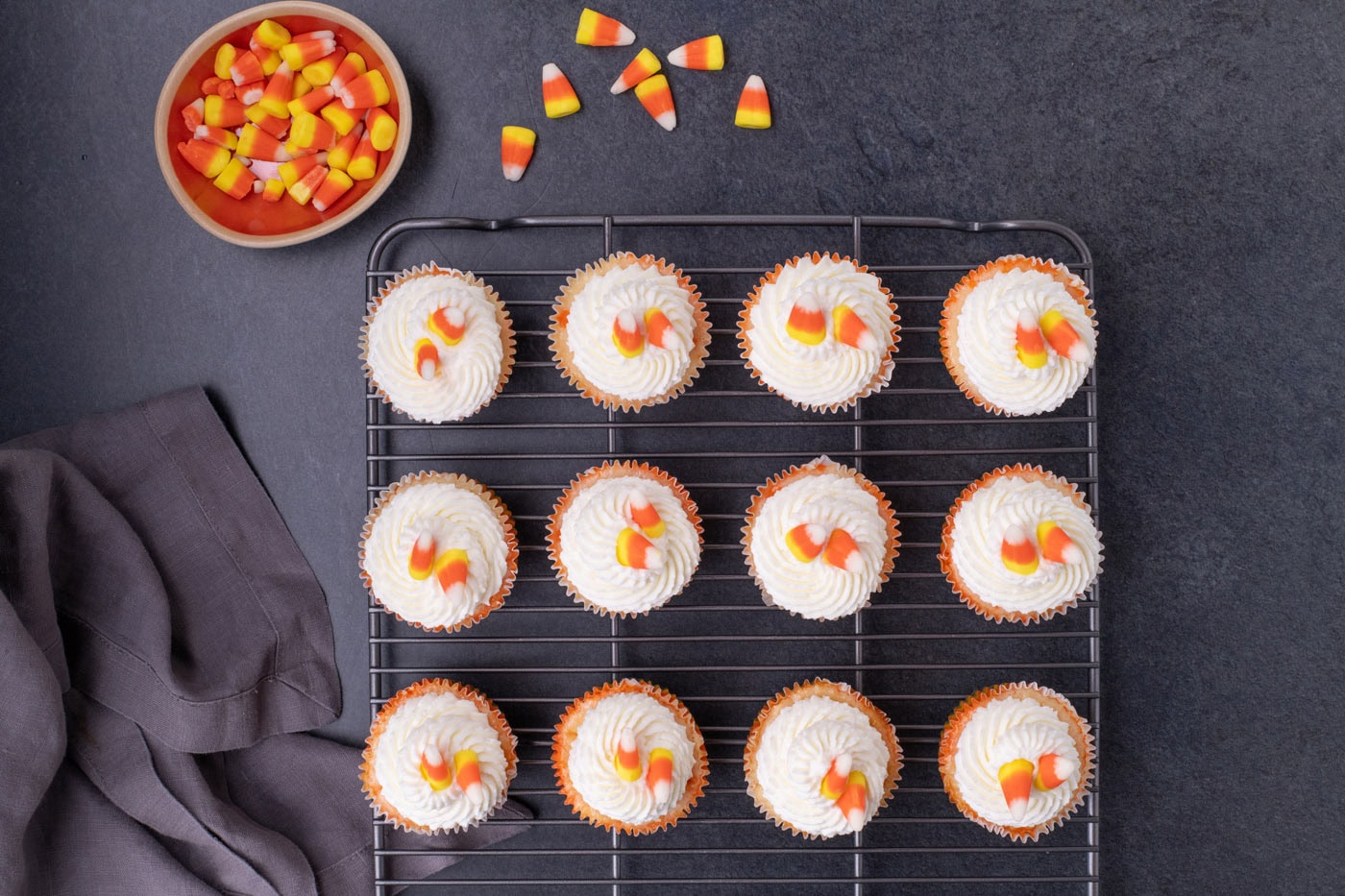 whipped cream and candy corn on top of candy corn cheesecakes on a wire cooling rack