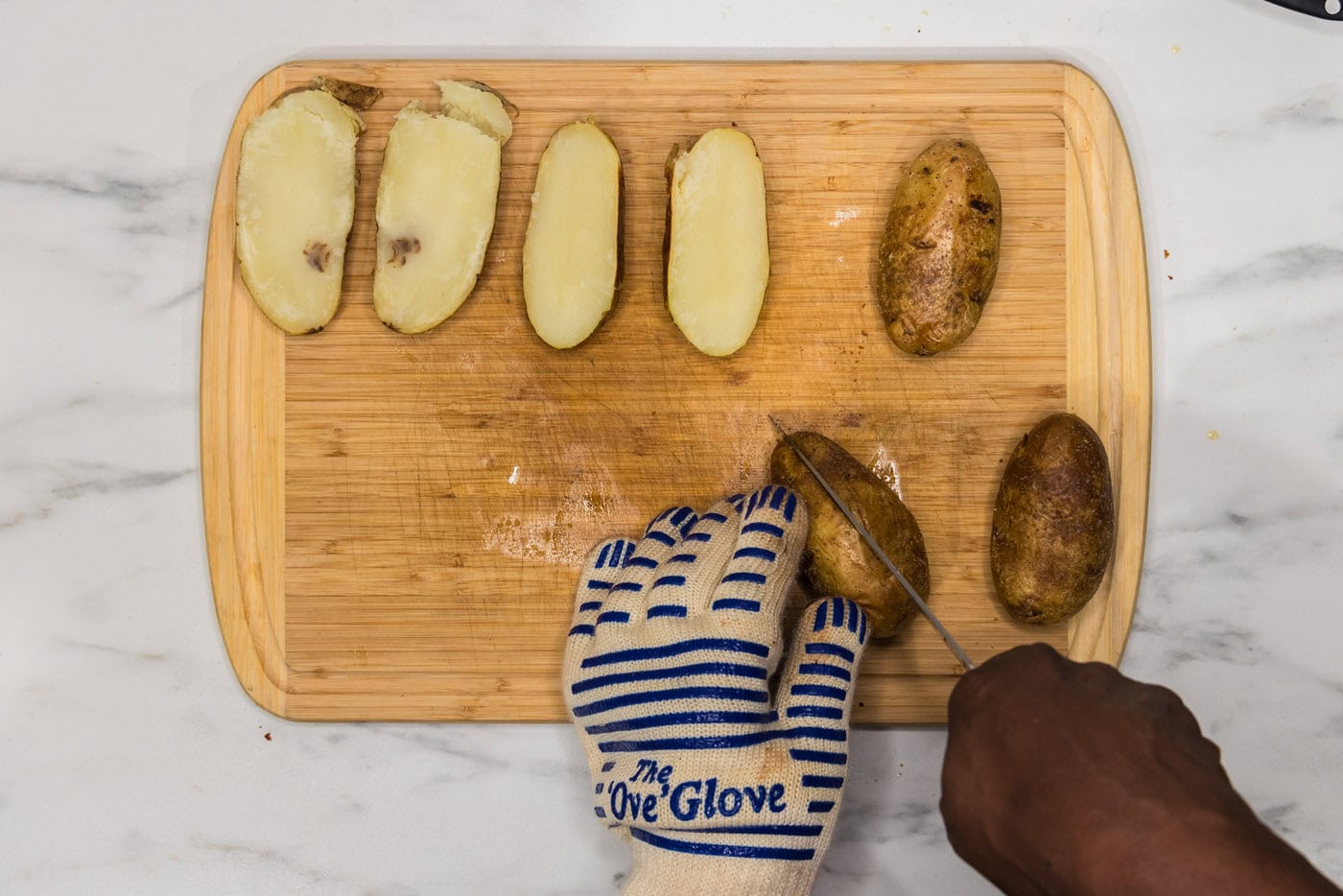 slicing potato in half lengthwise on a cutting board