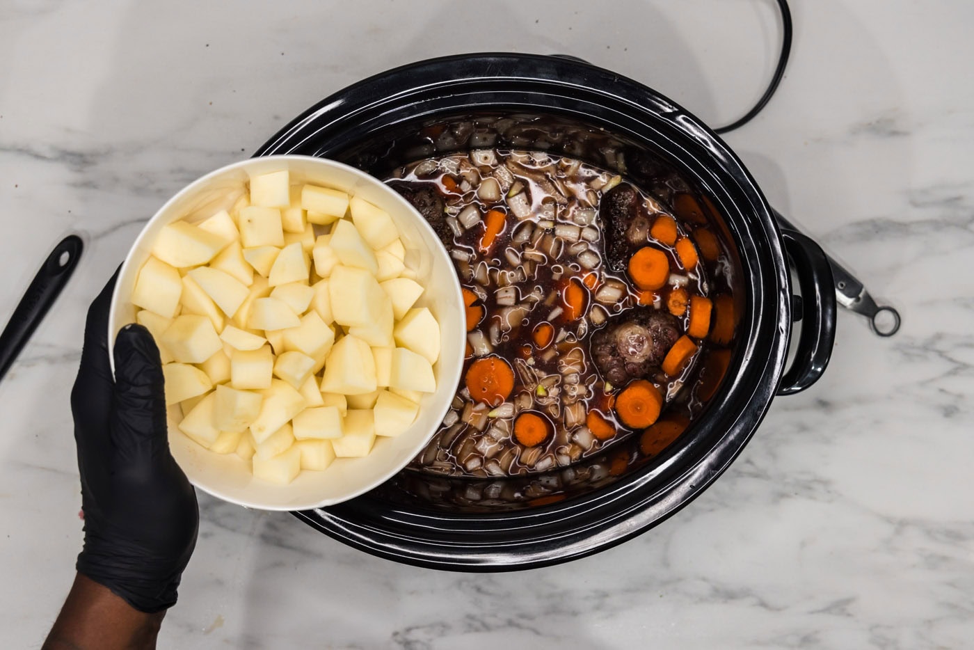 adding potatoes to slow cooker oxtail with carrots