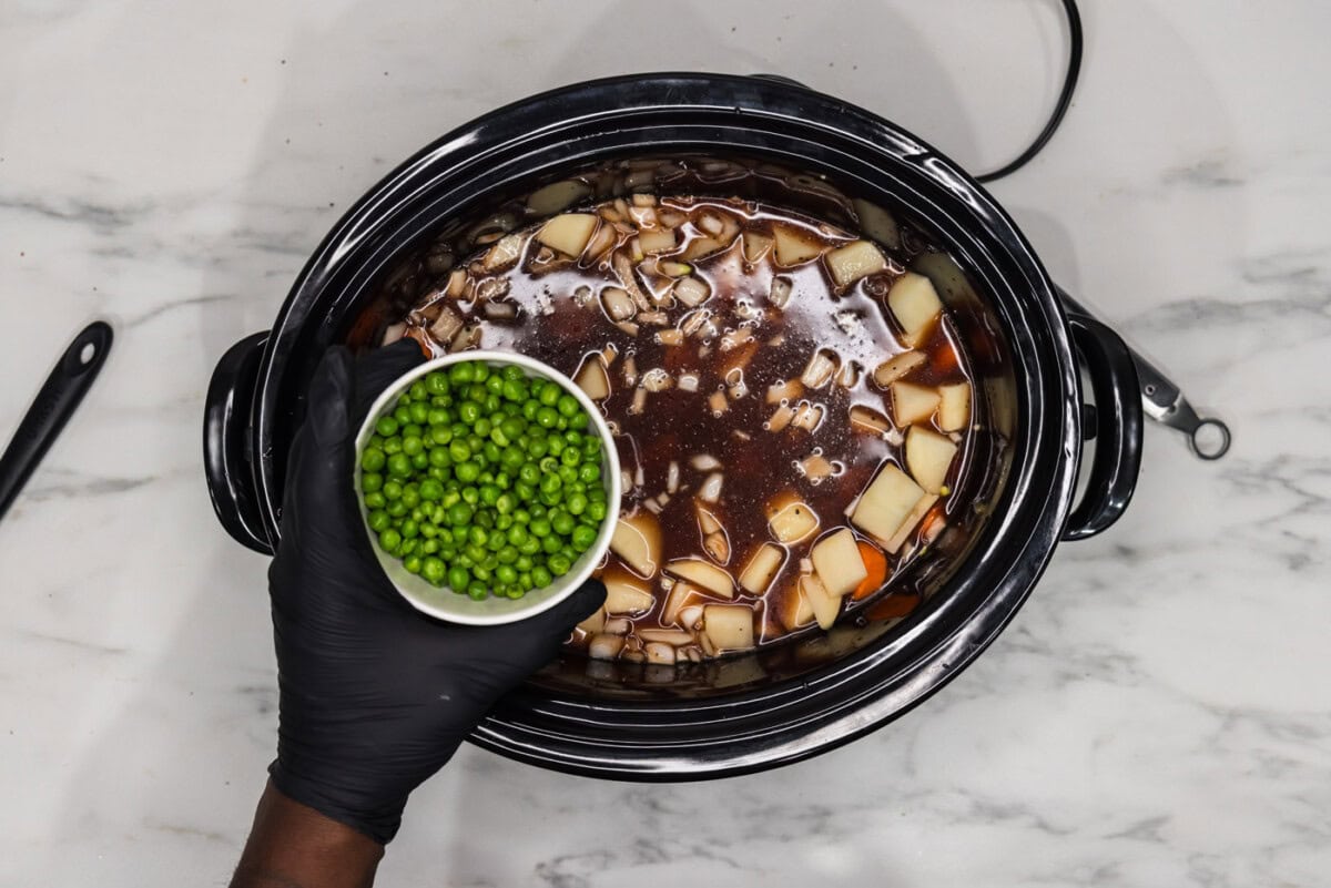 adding peas to potato and oxtail stew in crockpot