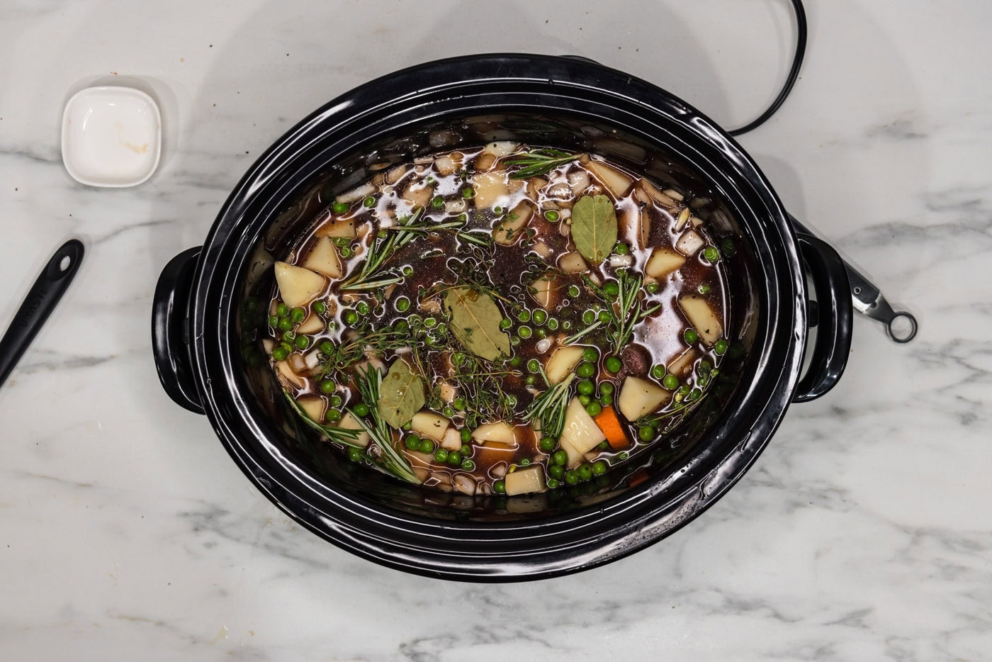 bay leaves and herbs added to slow cooker oxtail stew