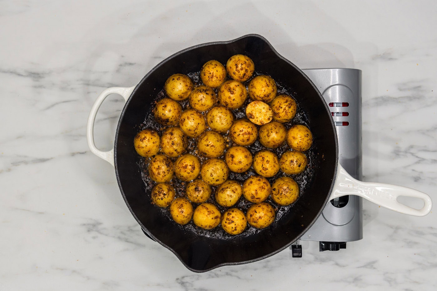 baby potatoes, skin side up, cooking in a skillet