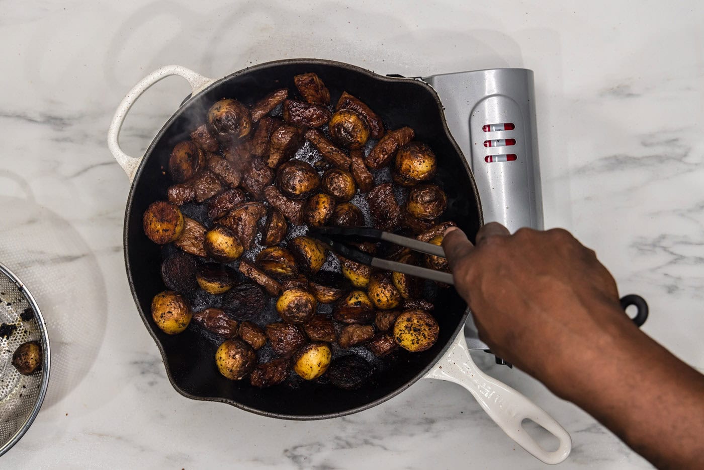 steak and potatoes cooking in a skillet