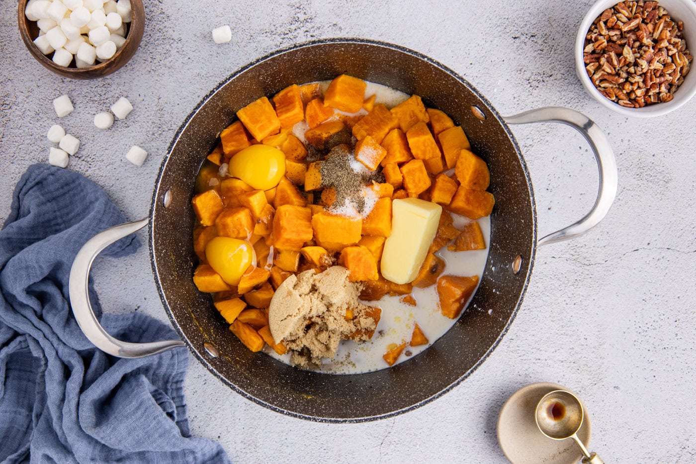 cubed sweet potatoes in a pot with butter, brown sugar, egg, and spices