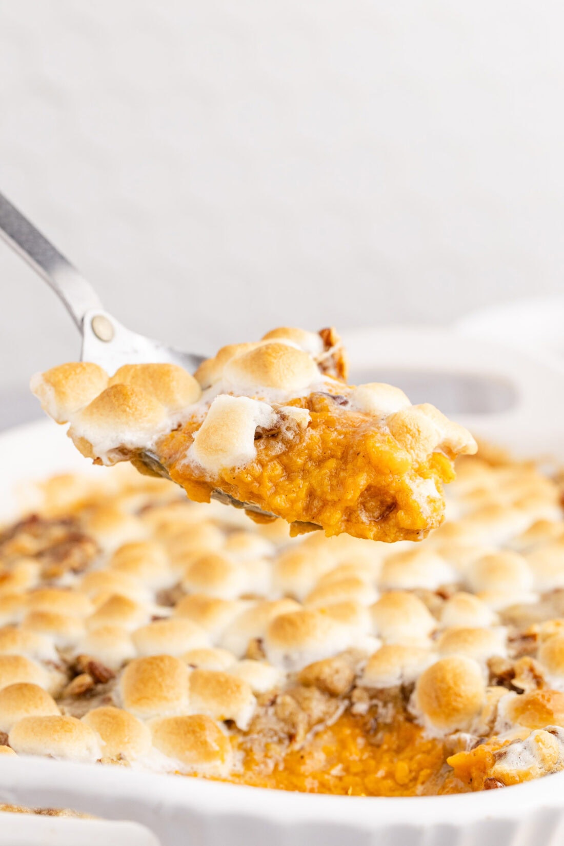 Spoonful of Sweet Potato Casserole held above the Sweet Potato Casserole