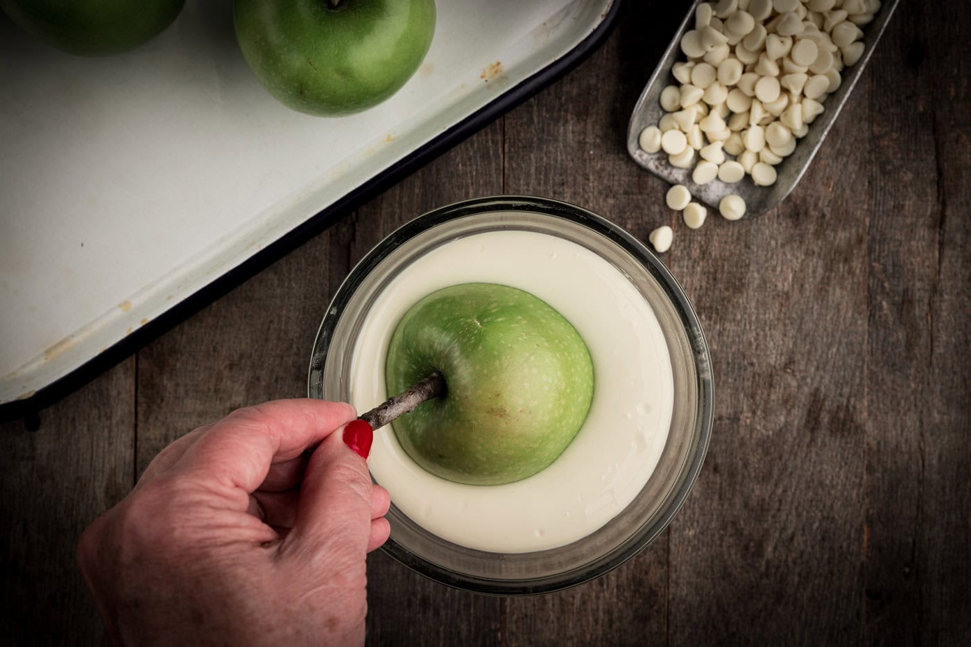 dipping skewered apple into melted white chocolate