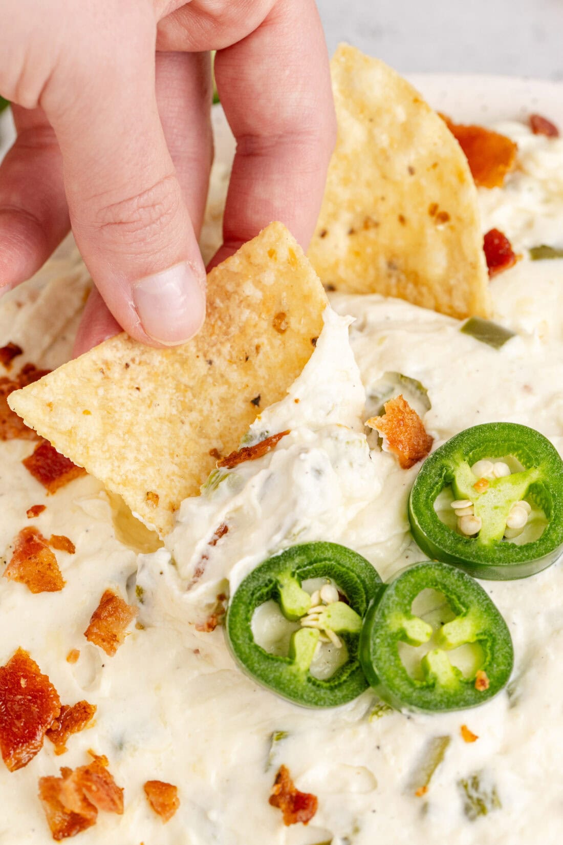 Chip being dipped into a bowl of Crockpot Jalapeno Popper Dip