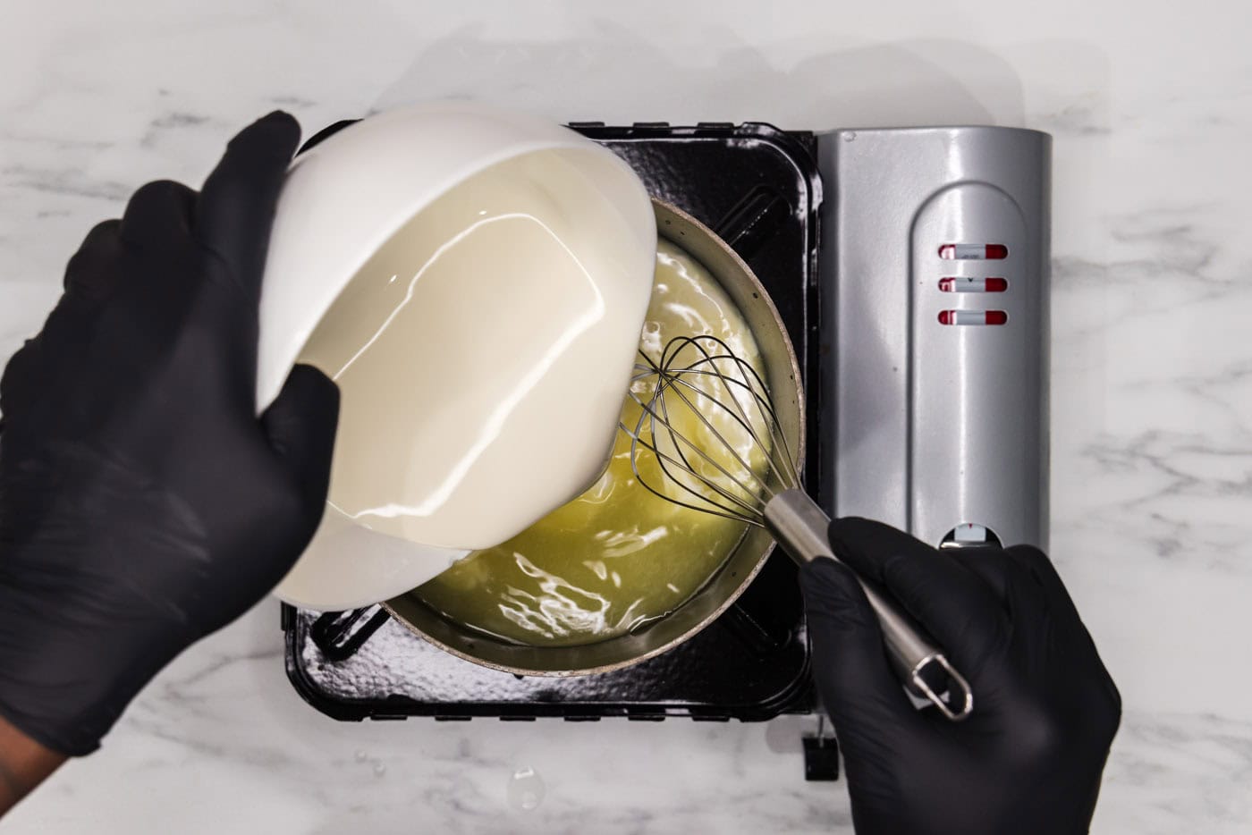 whisking heavy cream into a saucepan with water and chicken base