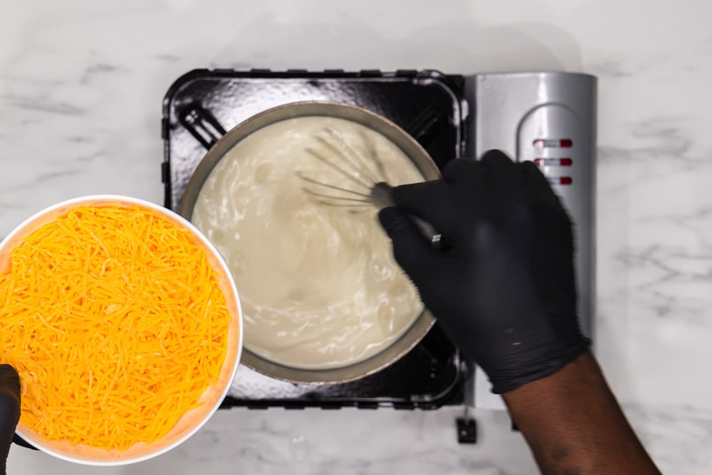 whisking heavy whipping cream mixture in a saucepan while adding cheese