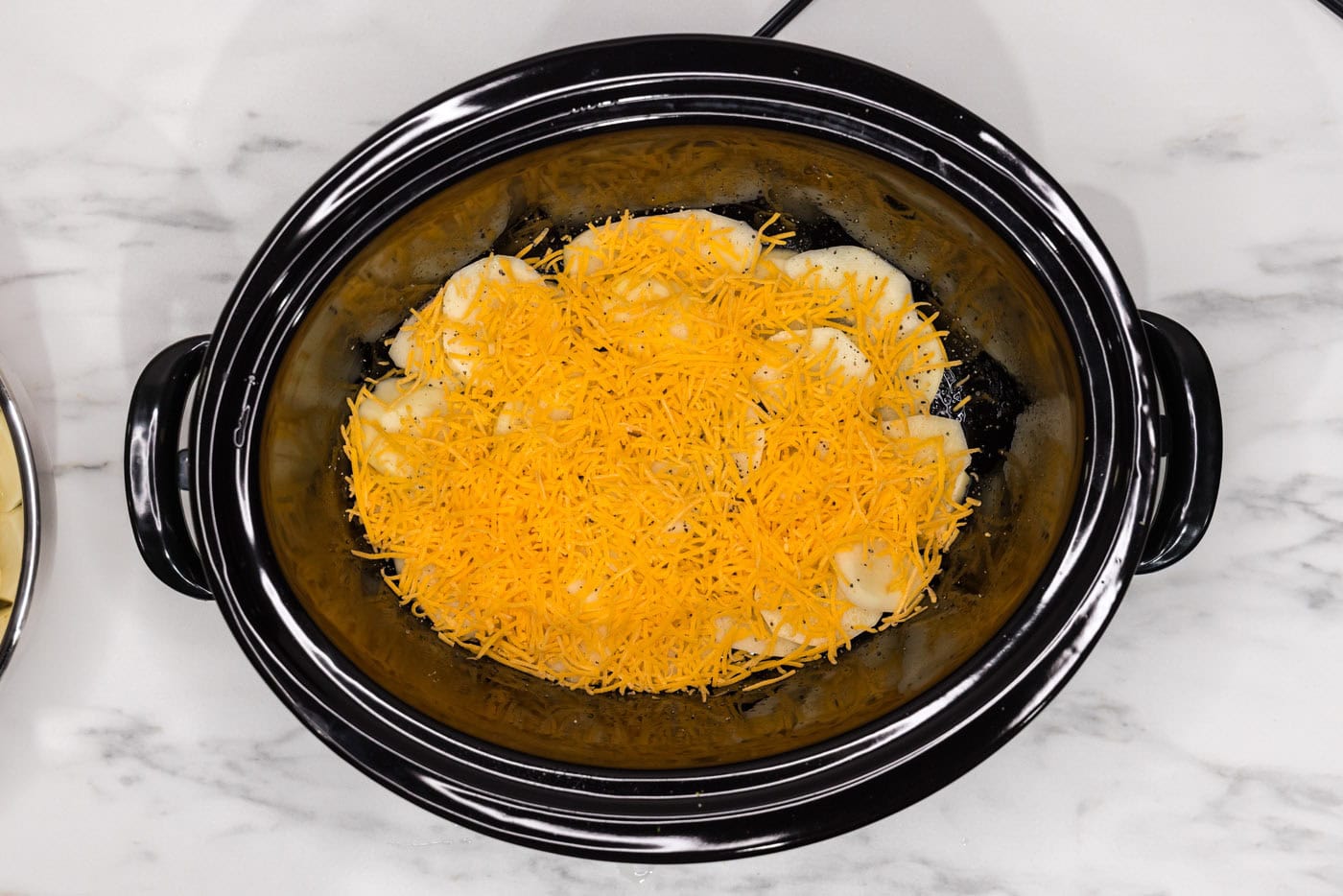 layer of cheddar cheese over sliced potatoes in a crockpot