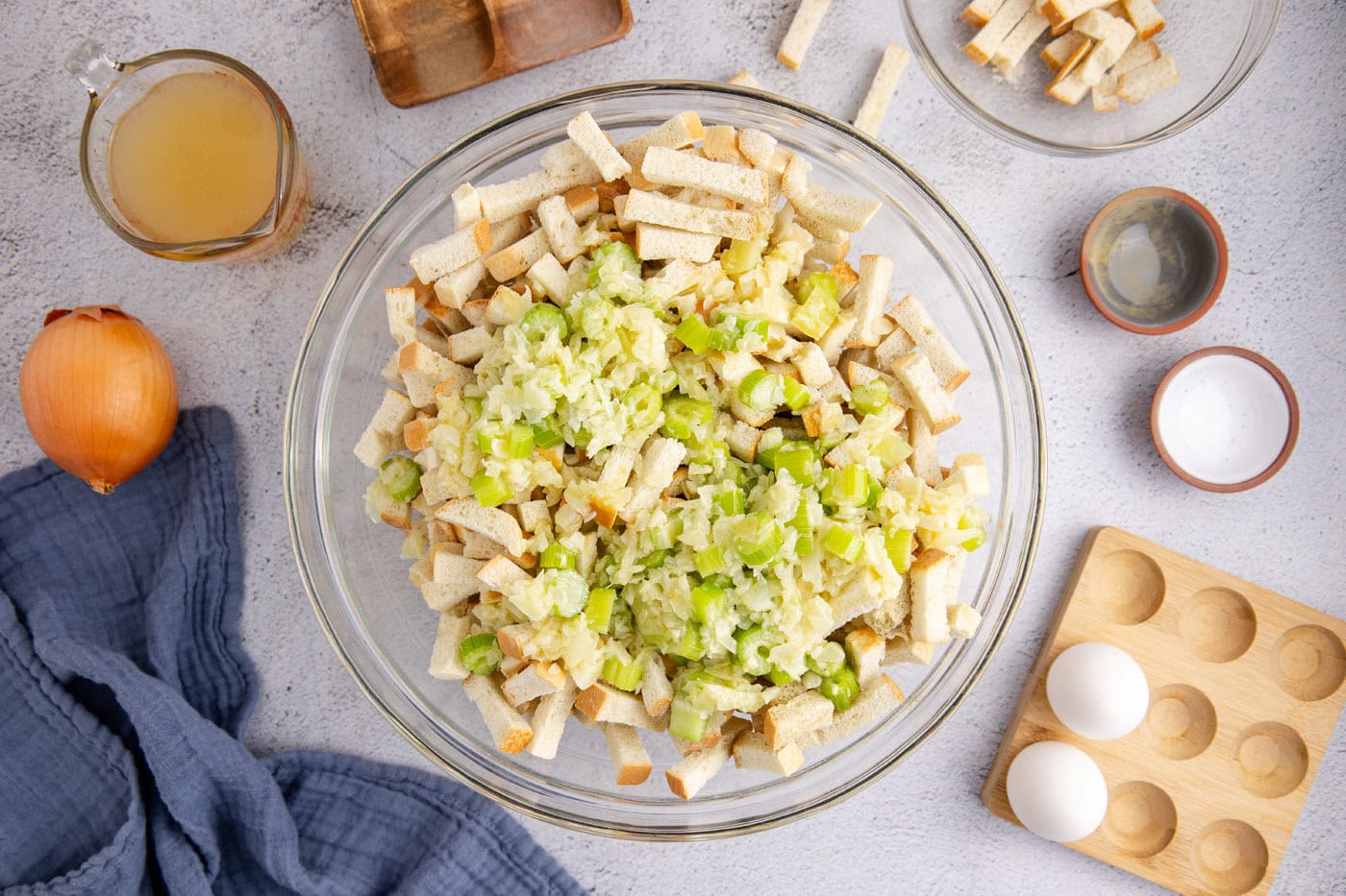 celery and onions mixture added to dried bread cubes in a bowl